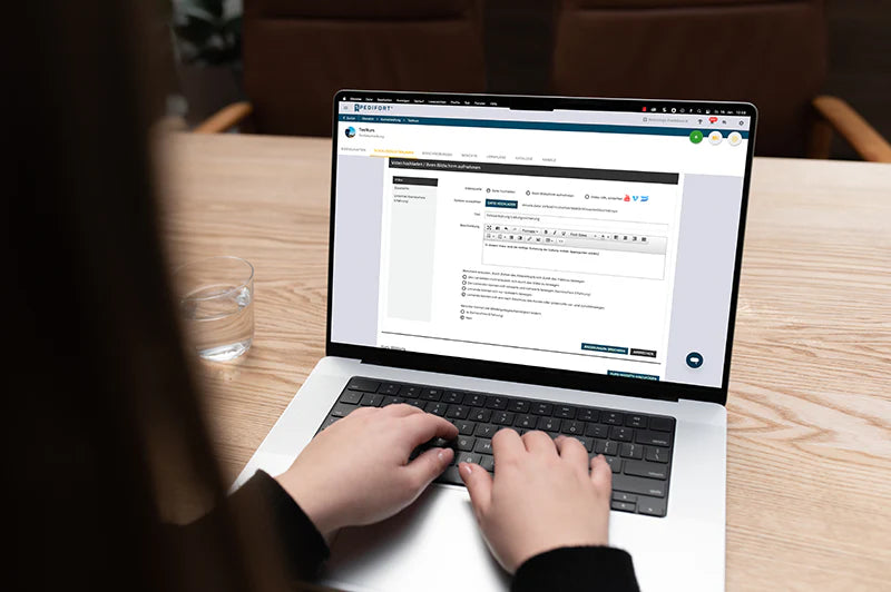 Person tippt an einem Laptop in einer Büroumgebung.