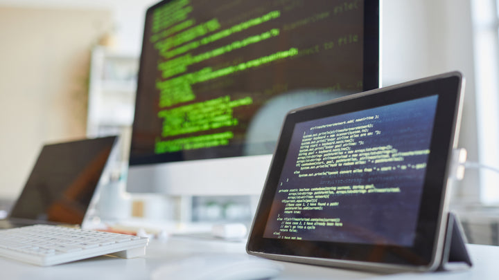 Bild eines digitalen Tablets und eines Computermonitors mit Software auf den Bildschirmen auf dem Tisch im IT-Büro.